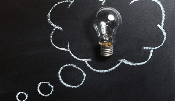 A light bulb inside a speech bubble drawn on a blackboard
