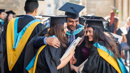 Graduating students smiling and hugging one another