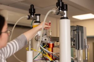 Woman places a sample into a high tech machine photo credit Tom Smith Photography